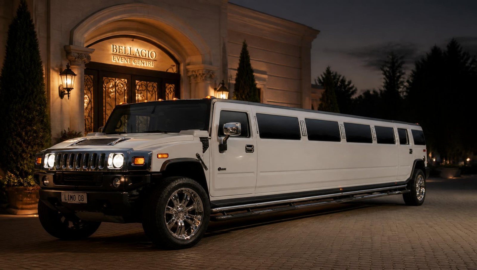 White Hummer H2 stretch limousine outside an event venue at dusk