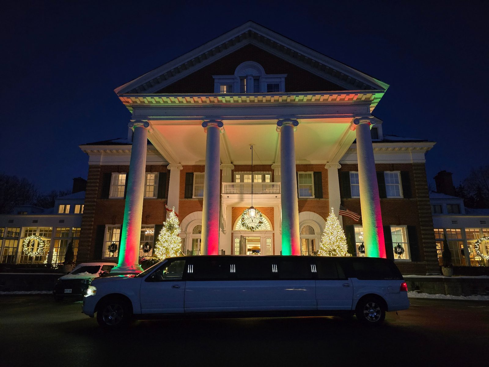 White stretch limousine parked outside an illuminated Toronto estate venue at night
