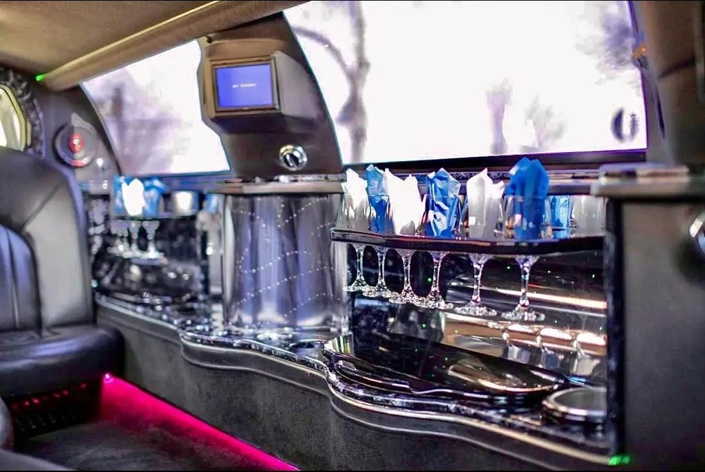 Limousine bar stocked with champagne glasses and napkins under LED lighting