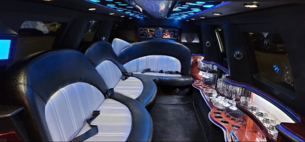 Stretch limousine interior with black and white leather seating, bar and blue LED lighting