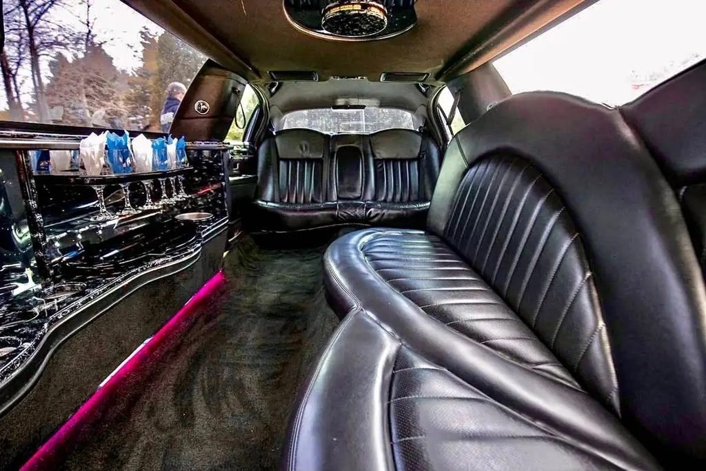 Stretch limousine interior in daylight with black leather seating and a mirrored bar