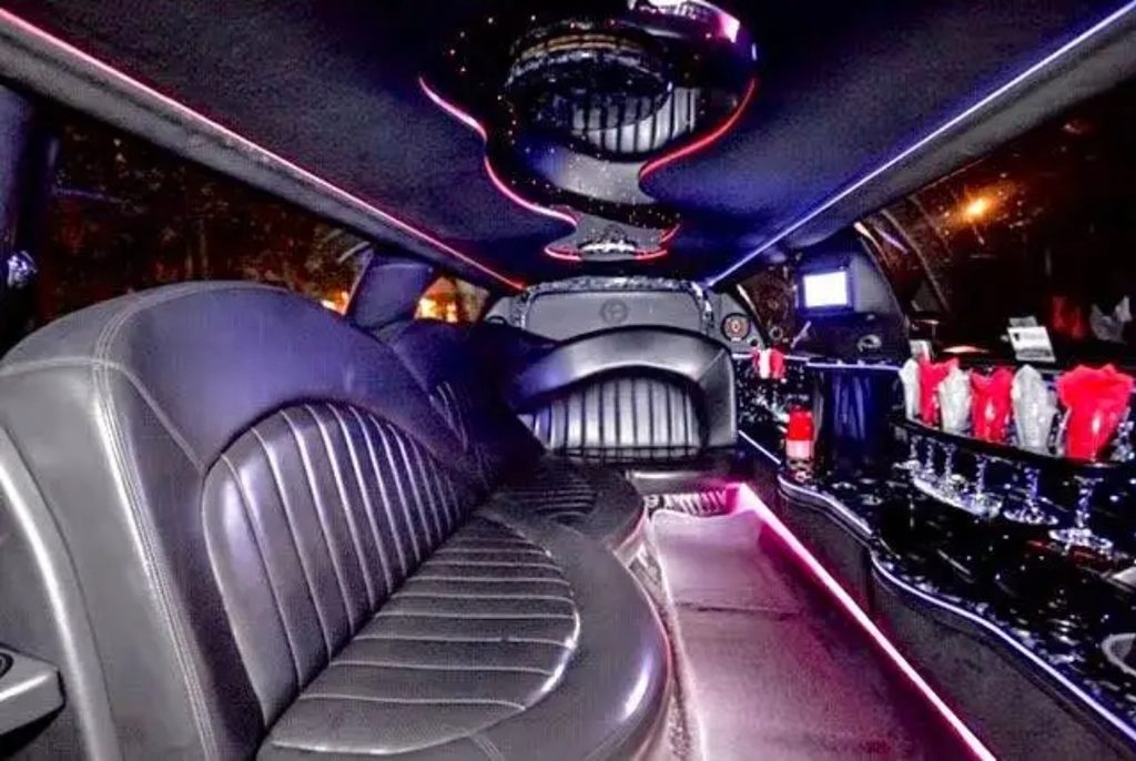 Limousine interior with purple and pink LED lighting, leather bench seating and bar