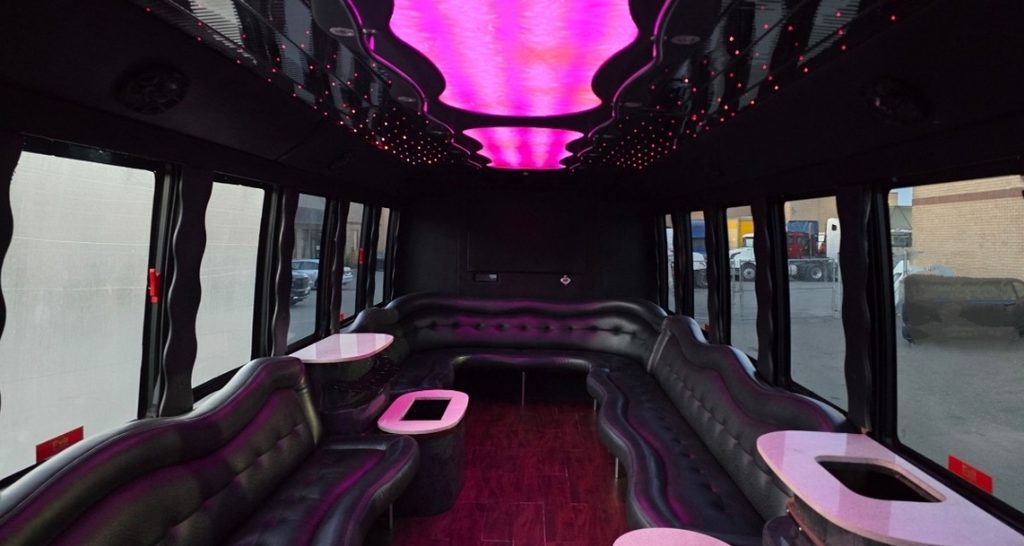 Party bus interior with LED ceiling lighting, leather bench seating and bar tables